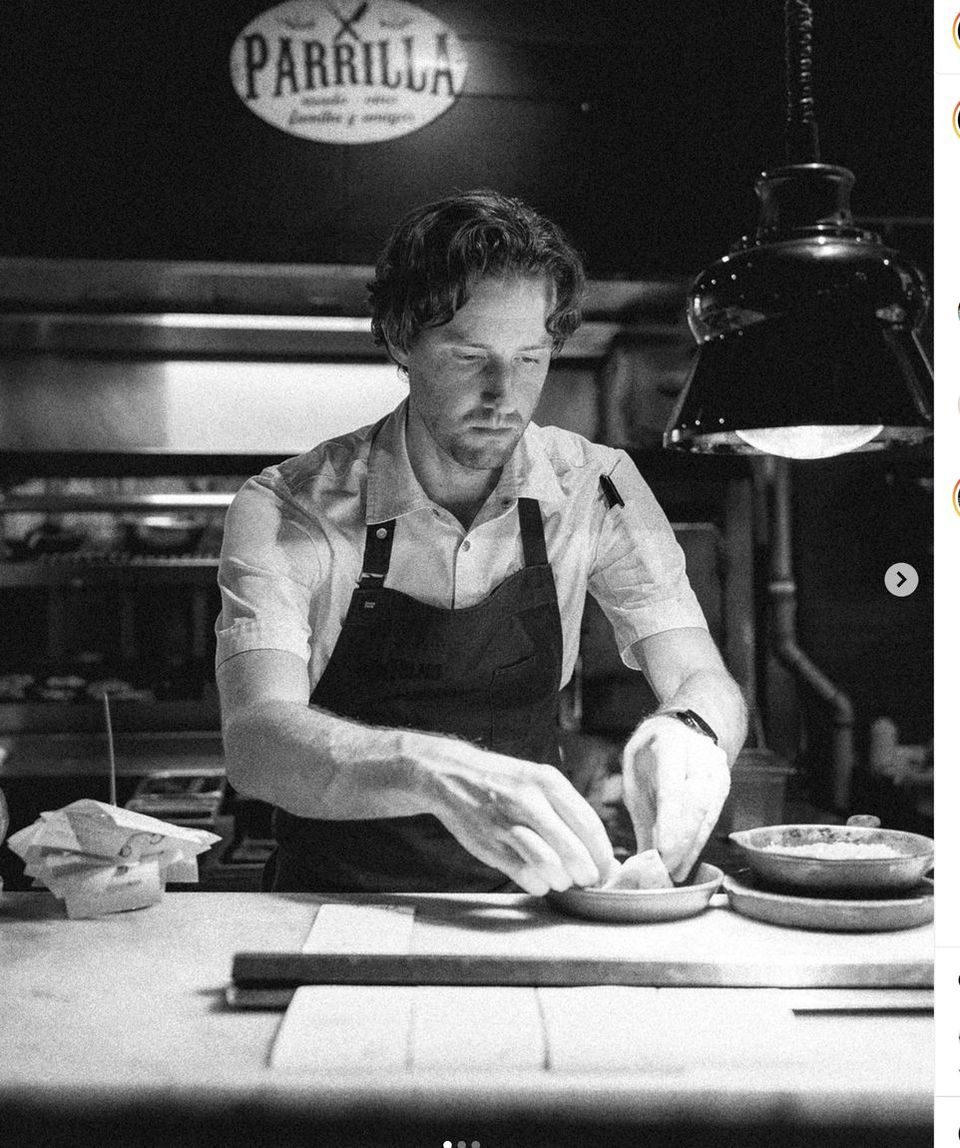 A chef plating a dish under the Parrilla sign, in black and white